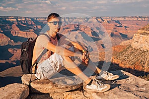 Young man sitting at the edge of the Grand Canyon