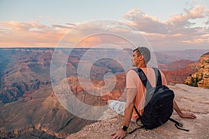 Young man sitting at the edge of the Grand Canyon