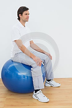 Joven hombre sobre el ejercicio esfera en gimnasia 