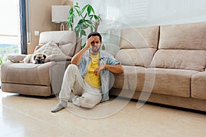 Young man sitting on the floor and holding his head in regret or disappointment