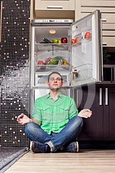 Young Man Sitting In Front Of Fridge