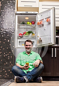 Young Man Sitting In Front Of Fridge