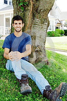 Young man sitting in front yard