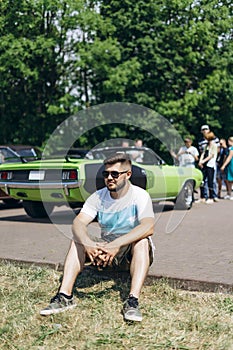 Young man sitting on green car background