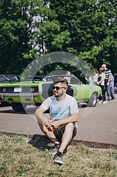 Young man sitting on green car background