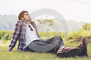 Young man sitting on green grass thinking