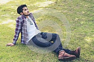 Young man sitting on green grass thinking