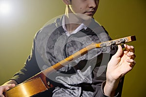 Young man sitting guitar tuning