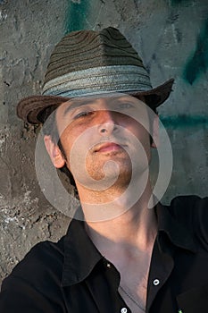 Young man sitting in hat near wall