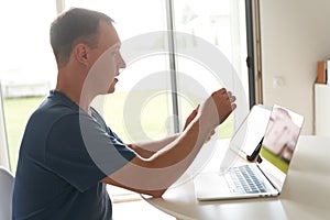 A young man sitting at home in front of a laptop. A serious person working remotely at home