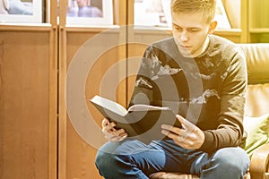 Young man sitting at home library and read a book, chill and relax f