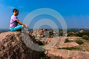 Young man is sitting on the mountain with beautiful view