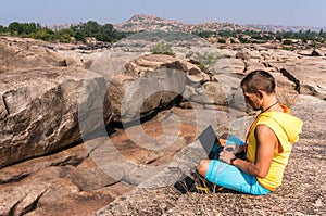 Young man sitting on the mountain with beautiful view and working with laptop