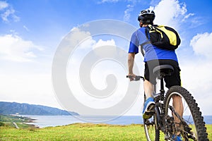 Young man sitting on a mountain bike and looking the ocean photo