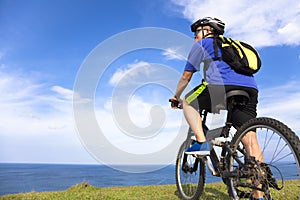 Young man sitting on a mountain bike and looking the ocean