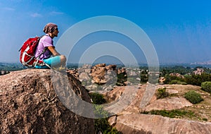 Young man sitting on the mountain and enjoying the view after trekking