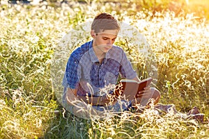 Young man sitting in nature reading a book