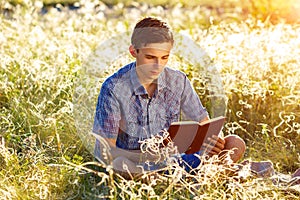 Young man sitting in nature reading a book