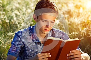 Young man sitting in nature reading a book