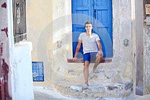 Young man sitting near old blue door of Emporio