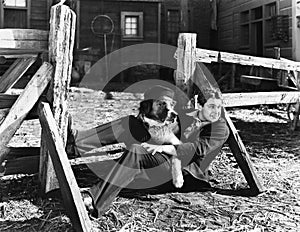 Young man sitting next to a fence with his dog