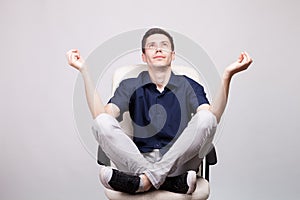 Young man sitting on an office chair with his feet up on the chair and hands in a relaxing pose