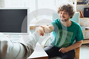 Young man sitting in office during the job interview with female employee, boss or HR-manager, talking, thinking, looks