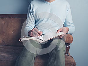 Young man sitting on old sofa writing