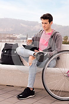 Young man sitting outdoors using tablet