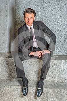 Young man sitting outside office building, relaxing, thinking