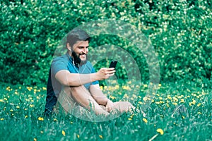 Young man sitting in the park and texting message