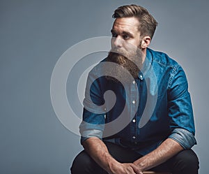 Young man sitting pensively against a gray background