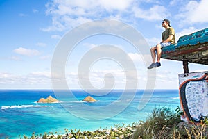 Young man sitting on pillbox over looking Lanikai looking out over the Pacific Ocean loving sitting on top of the world