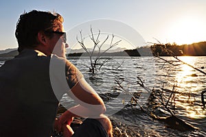 Young man sitting quietly beside lake