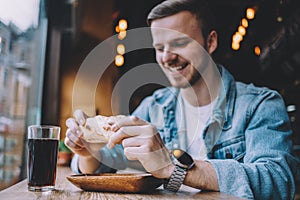 Young man sitting in a restaurant and eating a hamburger