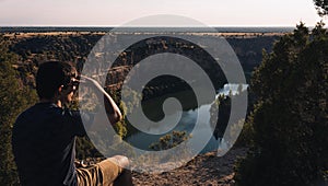 Young man sitting on a rock covering his face by the sun to observe the landscape of the DuratÃ³n River located in Segovia in