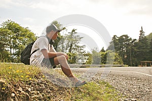 young man sitting by the side of the road