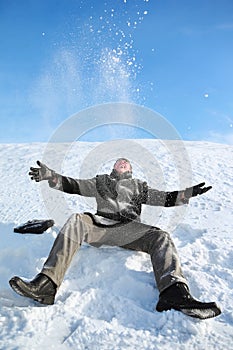 Young man sitting on snow and throw him upwards photo
