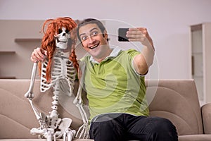 Young man sitting on the sofa with female skeleton