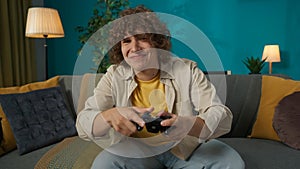 Young man sitting on the sofa in the living room playing video game