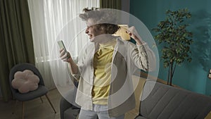 Young man sitting on the sofa in the living room and reading something on his smartphone HDR BT2020 HLG Material.