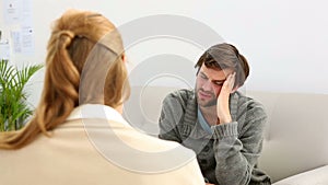 Young man sitting on sofa talking to his therapist