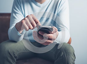 Young man sitting on sofa and using smart phone