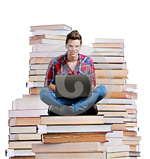 Young man sitting on a stack of books with a laptop