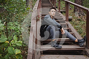 Young man sitting on stairs in forest