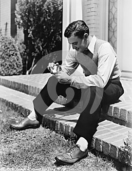 Young man sitting on a step and holding a cigarette lighter with a pipe