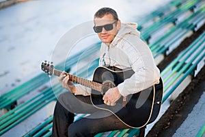 Young man sitting on steps playing guitar and singing