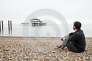 Young man sitting in a stone beach