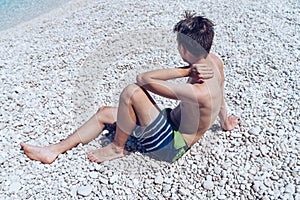 Young man sitting on a stone beach