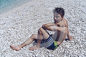 Young man sitting at a stone beach